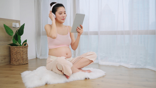 年轻孕妈盘腿坐着玩平板电脑视频