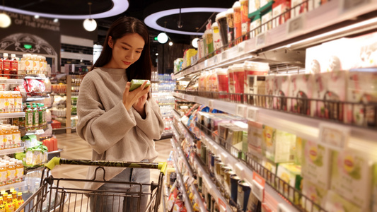 超市推着购物车的女青年挑选商品[加购]视频