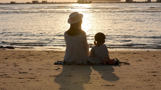 温馨母女海边沙滩坐着玩耍看日落视频