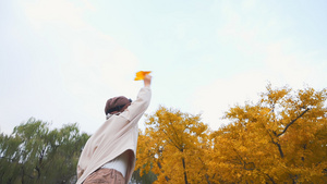 秋季公园草地上扔纸飞机的小男孩升格视频4秒视频
