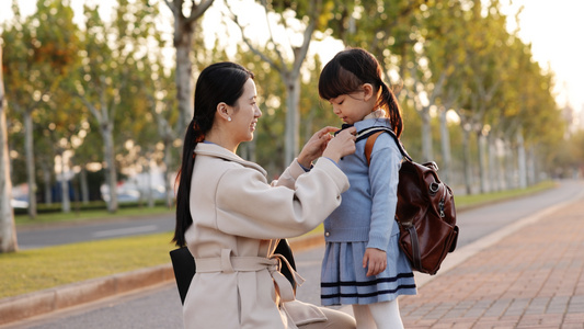 年轻妈妈在路边为女儿系好小领带视频