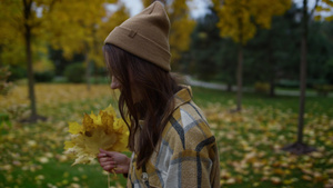 笑着有魅力的女孩侧面肖像用黄色的叶子手握着21秒视频