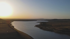 4k航拍夕阳下逆光的湖面和连绵起伏的山包59秒视频