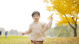 4K秋季公园草地上扔纸飞机的小男孩5秒视频