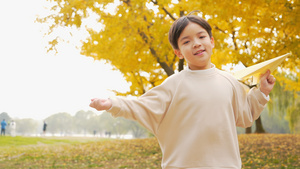 4K秋季公园小男孩在银杏树下扔纸飞机7秒视频