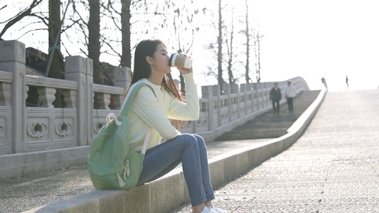 女生坐在石桥边喝奶茶视频