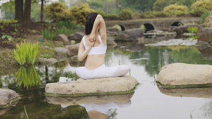 瑜伽女生坐在石头上做拉伸14秒视频