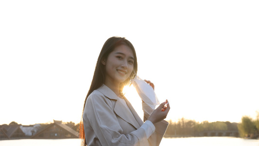 夕阳下女生在湖边摘下口罩微笑视频