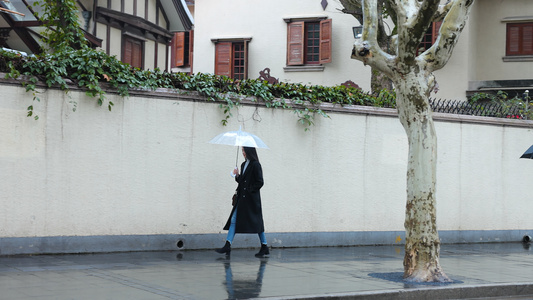 女人雨中撑伞漫步走在人行道上视频