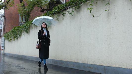 女人雨中撑伞漫步走在人行道上视频