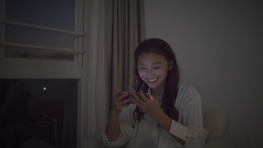 4K女性夜晚坐在窗边打手机游戏视频