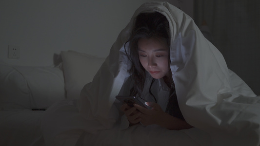 4K女性在被子里熬夜玩手机视频
