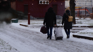 冬天下雪天气拉着行李箱出行的人们27秒视频