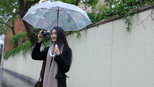 女人雨中撑伞漫步观光拍照视频