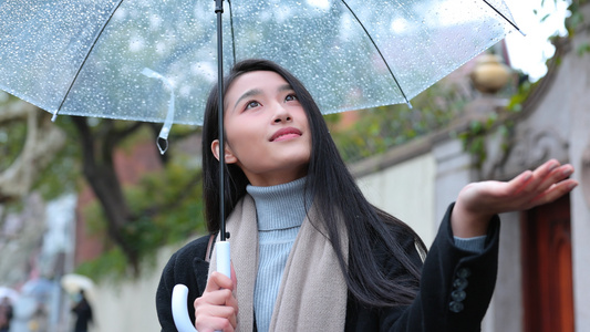 美女雨中撑伞伸手接雨水视频