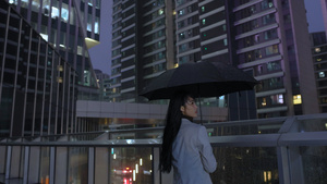 女人在商务楼下撑雨伞吹晚风18秒视频