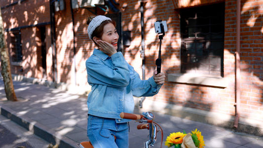 骑行的女青年在路边用手机自拍视频