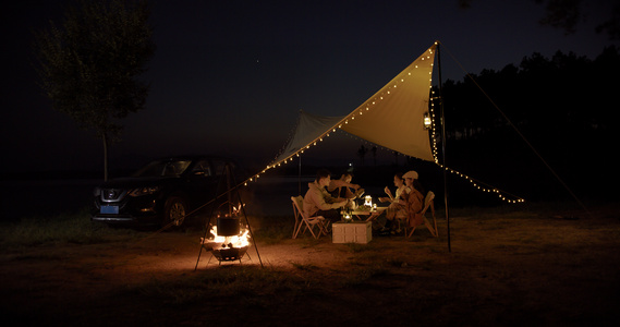 8K夜晚青年在篝火旁的帐篷里进行晚餐视频