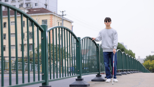 手扶栏杆使用盲杖行走的盲人视频