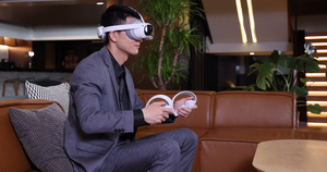 商务人士坐在沙发上玩VR游戏机9秒视频