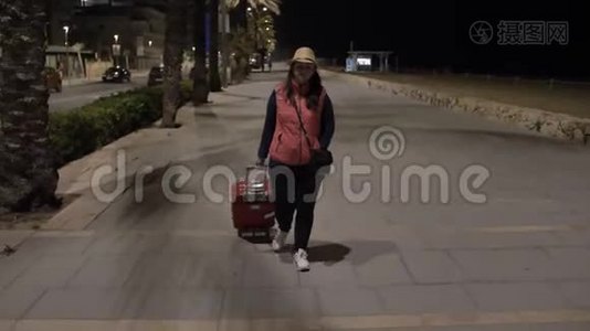 女游客晚上带着一个手提箱沿着长廊走视频