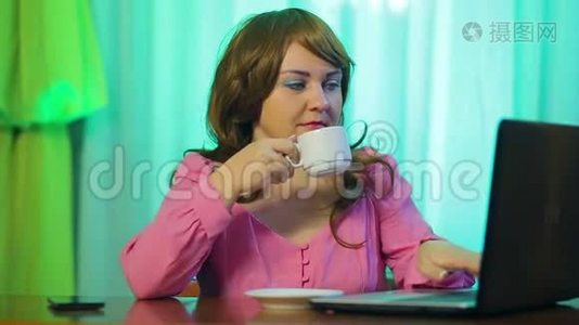 红发女人在咖啡馆的一张桌子上喝咖啡，和一台电脑一起工作视频