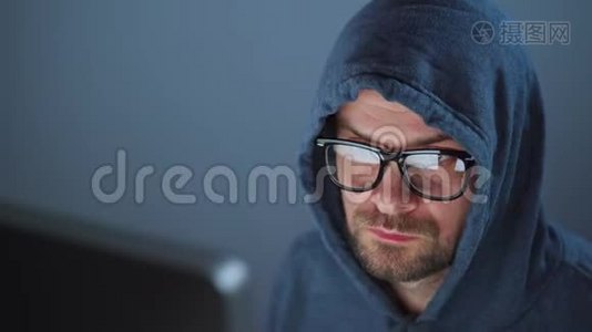 戴着头巾的男黑客和戴着眼镜在黑暗的办公室里用电脑工作。 网络犯罪概念视频