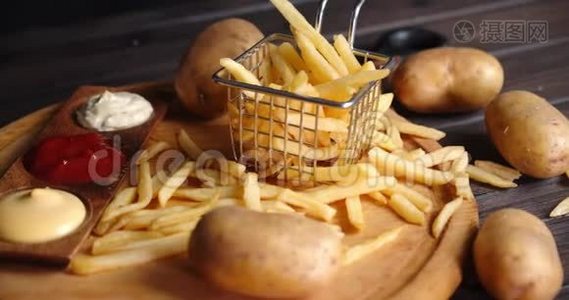 炸薯条放在切菜板上的篮子里，里面有各种酱汁。视频