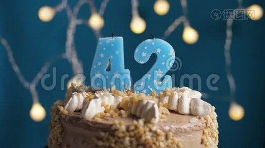 生日蛋糕，蓝色背景上有42支蜡烛。 蜡烛吹灭了。 慢动作和特写视频