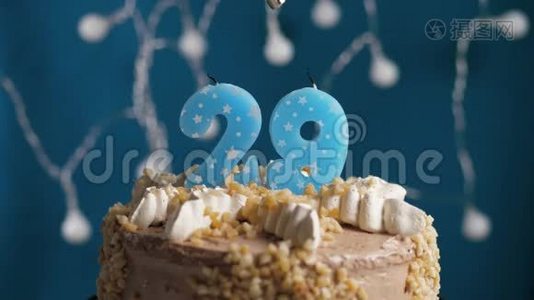 生日蛋糕，蓝色背景上有29支蜡烛。 蜡烛吹灭了。 慢动作和特写视频