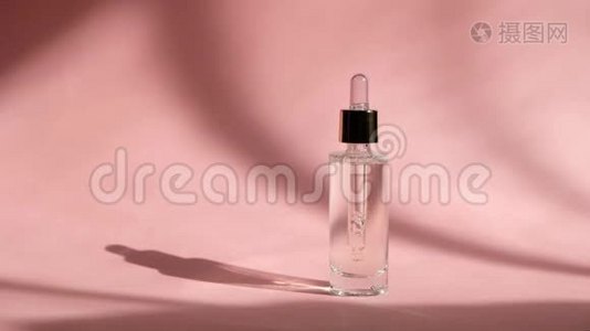 将血清滴在粉红色背景的透明玻璃瓶中，并`女士的手。 护肤美容，美容精华视频