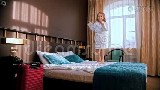 一个小女孩跳在旅馆房间的床上视频