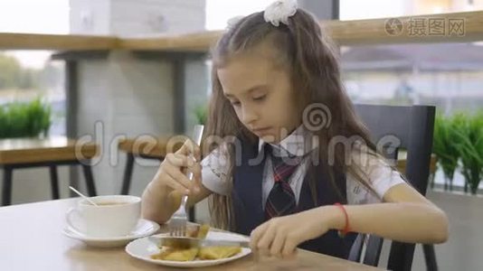 学生小学穿着校服坐在学校食堂的一张桌子东西。视频