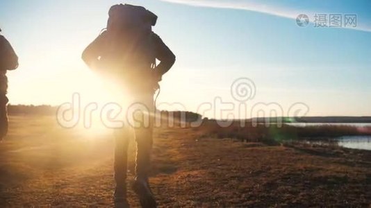 两名游客一起背着背包，慢动作行走，在阳光下剪影，在生活方式的夕阳下视频