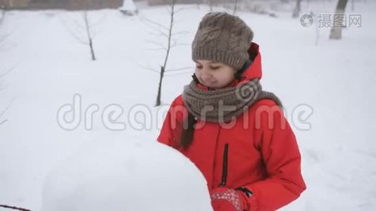 少女在街上玩冬天。 女孩雕刻雪人雪。视频