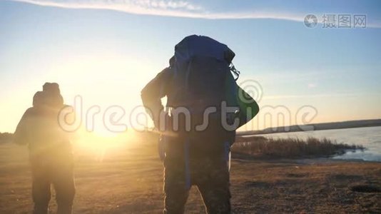 两名游客一起背着背包，慢动作行走，在阳光照射下的生活方式中剪影视频
