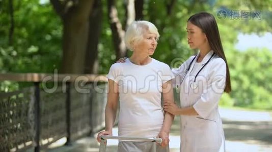 坐着步架的老年妇女和看镜头的女性治疗师视频