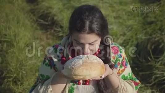 可爱的超重女人坐在草地上嗅着美味的面包准备吃的肖像。 传统观念。 国家视频