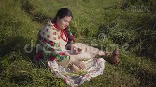 美丽的超重女人坐在草地上吃着新鲜的面包和黄瓜。 传统视频