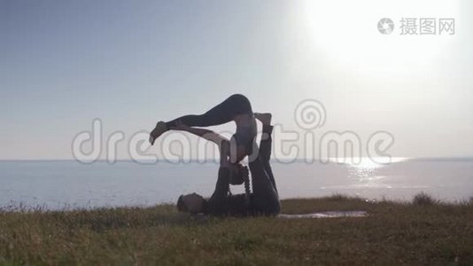 健康的生活方式，瑜伽双人正在草地上做运动，享受大自然，海洋的清新空气视频