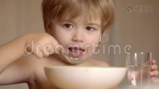 快乐的小男孩勺子吃自己。 快乐的孩子吃早餐。 快乐的孩子。 嘲笑可爱的小孩坐在视频