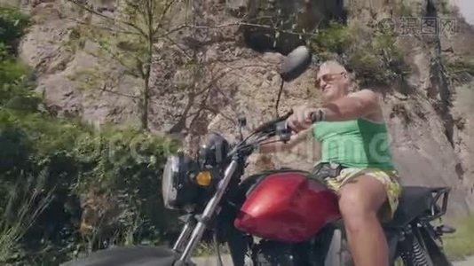 夏天旅行时，野蛮人骑摩托车在公路上欣赏山景。 关闭高级摩托车手视频