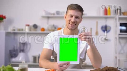 帅哥拿着绿色屏幕的平板电脑，烹饪课程申请视频