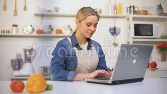 穿围裙的年轻美女在网上博客上搜索食物配方视频