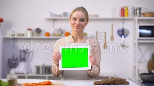 开朗的女人拿着绿色屏幕的平板电脑，烹饪博客和应用程序模板视频