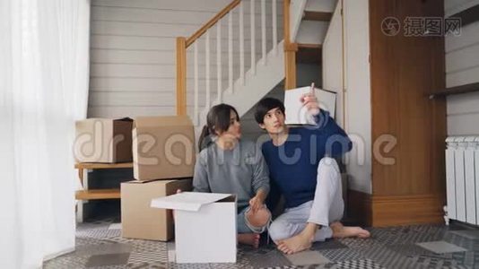 女朋友和男朋友正在谈计划，坐在新买的房子的地板上，环顾四周，表达自己的想法视频