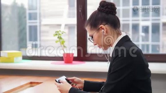 商业概念。 一个戴耳机的女人用手机上网视频
