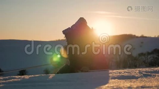 登山者到达雪山的顶端。 一个背着背包的登山者爬上了雪坡。 日落的天空视频