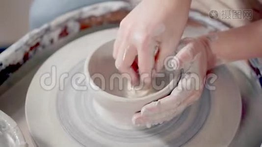 女人在陶工`的陶轮上润湿和软化粘土，特写视频