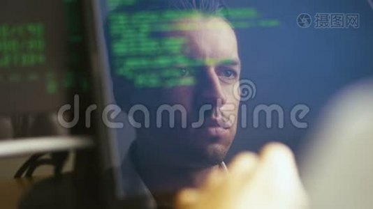 一个黑客程序员在笔记本电脑前工作的双重曝光照片。监视器中的反射：开发人员编写绿色代码。视频